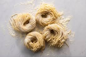 Four nests of fresh spaghetti resting on a floured surface.