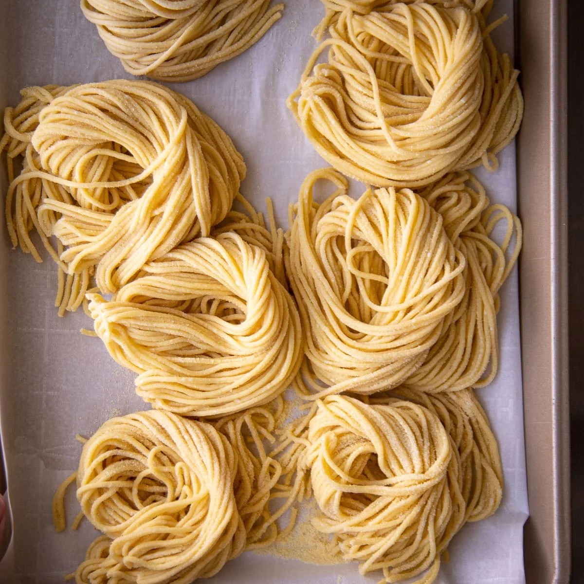 Tray of freshly extruded spaghetti nests dusted with semolina.